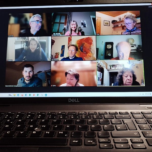 ein aufgeklappter Laptop mit 9 Personen am Bildschirm bei einem Zoom Meeting