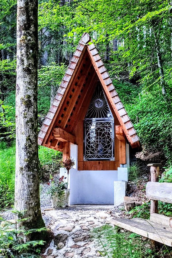 eine Kapelle im Wald mit Holzschinteldach