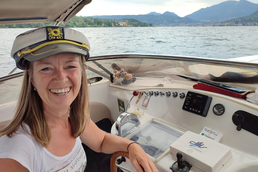 eine Frau trägt eine Kapitänsmütze und steuert ein Schnellboot